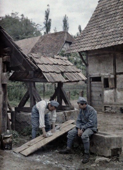 Twee Franse soldaten verzorgen hun wasgoed met behulp van planken op de trog van een fontein nabij een boerderij in de stad Gildwiller, Departement Haut-Rhin, Elzas, Frankrijk, 21 juni 1917 door Paul Castelnau